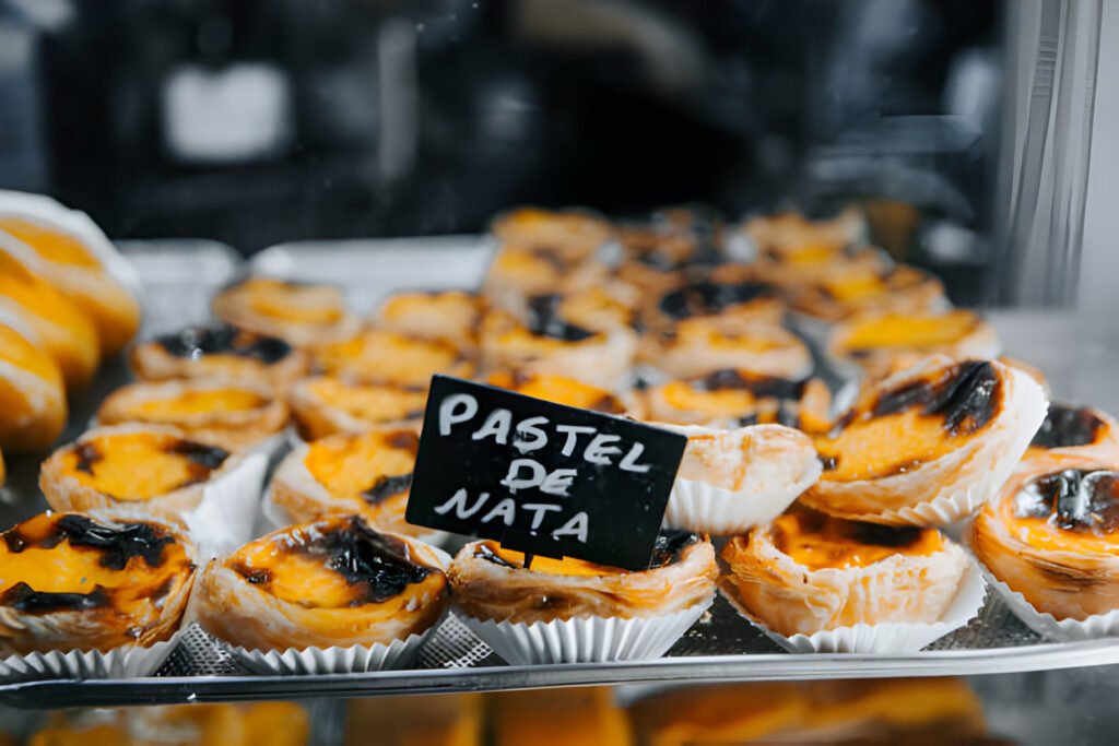 A group of digital nomads in portugal working on their laptops in a picturesque Portuguese café, with scenic views of the coastline in the background.