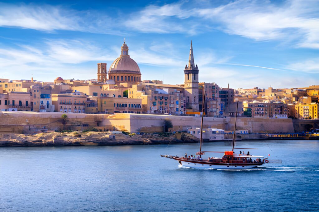 !<Malta, Valletta skyline with St. Paul's Anglican Cathedral and Carmelite Church as seen from Sliema. The image features the stunning architectural landmarks rising above the historic cityscape, with the calm Mediterranean Sea in the foreground. Digital Nomad Visa 2024.