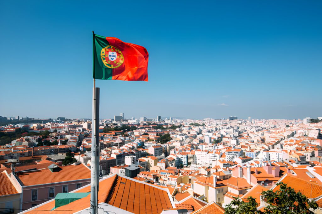Portugal Digital Nomad Visa: Portuguese flag waving proudly over the picturesque skyline of Lisbon, showcasing the vibrant culture and stunning architecture that await digital nomads in Portugal.